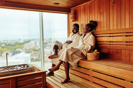 A young wealthy African American couple is sitting in a sauna enjoying their luxurious weekend.