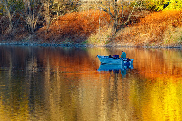 A fishing boat with two fisherman on a lake in autumn