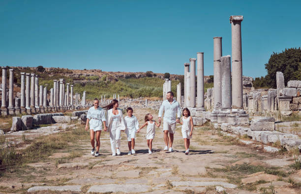 온 가족이 거대한 기둥 사이에서 고대 도시의 역사적인 거리에서 손을 잡고 걷고 있습니다. 훌륭한 문화 여행. - turkey tourist ephesus roman 뉴스 사진 이미지