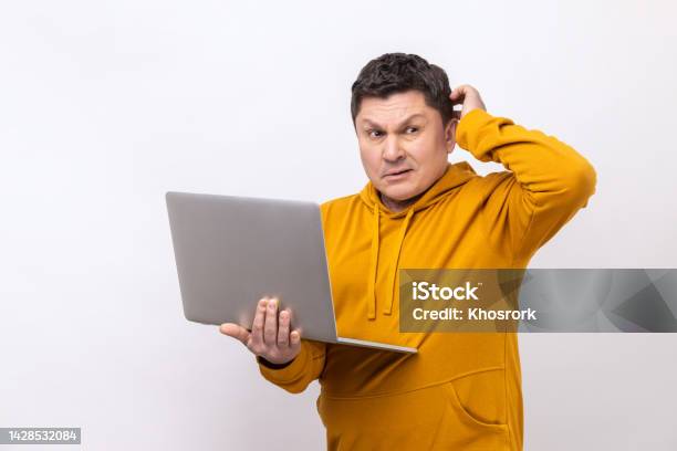 Pensive Man With Holding Laptop And Rubbing Head Looking Away Thinking Over New Business Project Stock Photo - Download Image Now