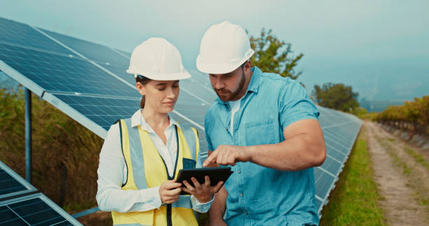 Solar panel, engineer and talk with tablet for project data analysis with eco contractor team. Construction, sustainability and renewable energy development with professional technician. stock photo