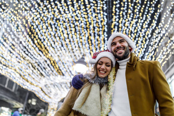 una giovane coppia alla moda si sta godendo una passeggiata in città durante una notte fredda. - fun knit hat adult dating foto e immagini stock