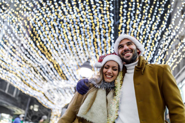 um jovem casal da moda está curtindo a caminhada da cidade durante uma noite fria. - fun knit hat adult dating - fotografias e filmes do acervo