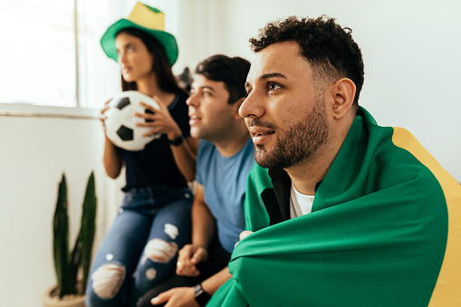 Fanáticos de los deportes nerviosos y emocionados viendo el juego en la televisión en casa. Amigos nerviosos viendo el partido de fútbol en el sofá. photo
