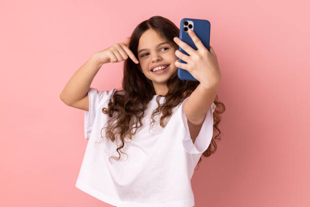 istock Little girl pointing down while communicating by video call or streaming, gesturing to subscribe, 1428535080