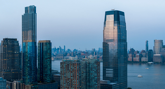 Paulus Hook in Jersey City with Portside Towers apartments and Goldman Sachs Tower. Remote view of Lower Manhattan over the Hudson River at dusk.