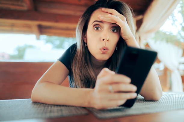 Surprised Girl Receiving a Strange Text Message Woman waiting in a restaurant reading shocking news on her phone concepts topics stock pictures, royalty-free photos & images
