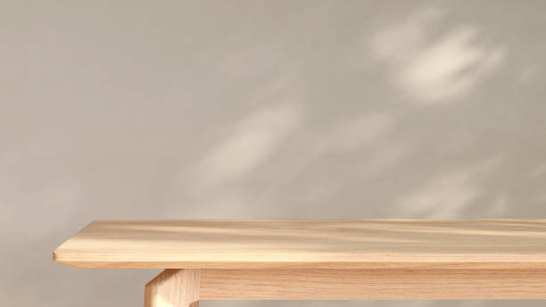 istock Wooden tabletop in sunlight from window with leaf shadow on cream beige wall background 1428540241