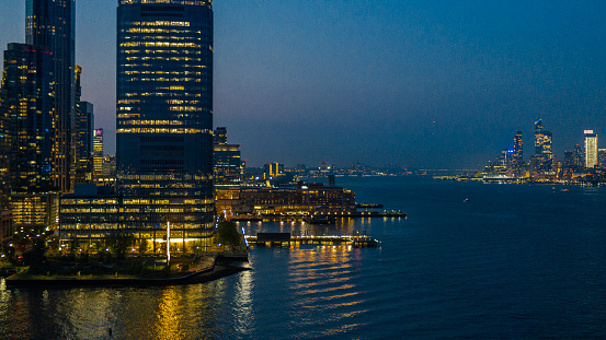Jersey City along the Hudson River, with the remote view of Hudson Yards, illuminated at night.