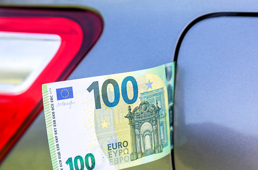 Euro banknotes under the fuel tank cap of a car. Concept photo of the rising fuel price
