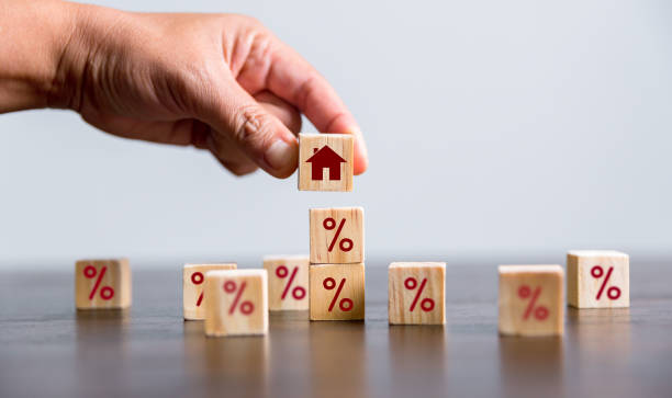 Hand building a house by wooden cubes with the percentage sign on them. Concept of Interest rate financial mortgage rates, home loans, home refinance, wooden block with percentage symbol and up arrow. stock photo