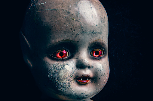 A close up of a creepy baby doll that look like a little demon.