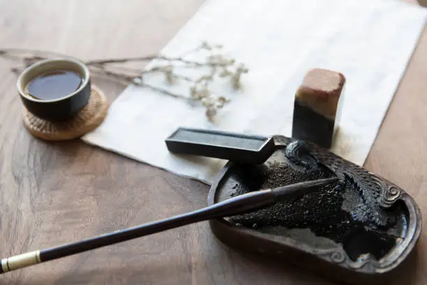 Photo of Traditional Chinese writing instruments, brushes and Xuan paper, inkstones, seals and Chinese green tea