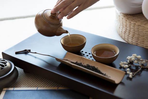 nalewanie herbaty, zestawy do herbaty, tradycyjna chińska sztuka herbaty, kultura herbaty, wykwintne palniki kadzideł, futon, tradycyjne chińskie książki - chinese tea zdjęcia i obrazy z banku zdjęć