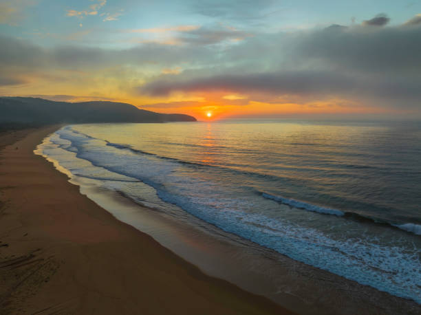istock Peaceful sunrise over the ocean with small waves and clouds 1428567360