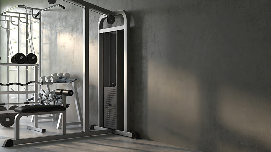 Luxury gym, exercise and sport equipment in modern gray concrete room at home with sunlight from window in background