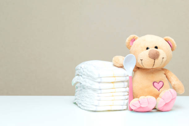istock Stack of diapers with toy teddy bear with spoon on table. set for baby shower with copy space 1428568897