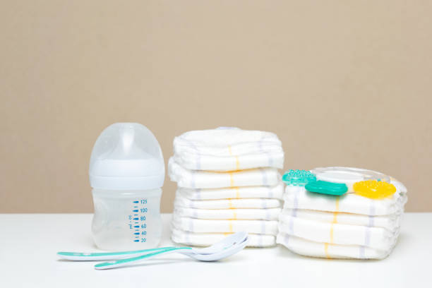 istock Stack of diapers with bottle of milk and spoons on table. baby's stuff with copy space 1428568902
