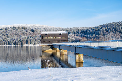 Intake tower of Josefuv Dul Dam and access bridge on sunny winter day, Czech Republic