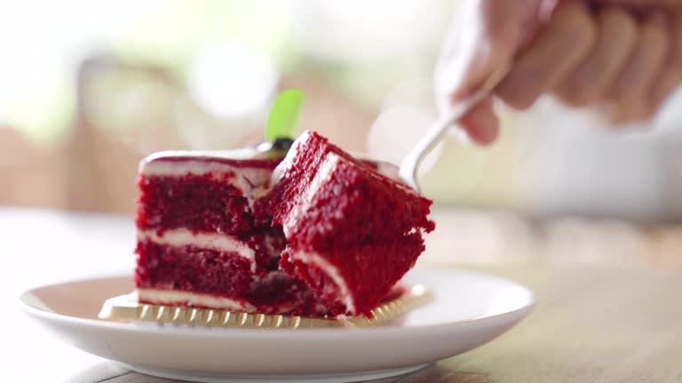 Hand holding a fork cutting delicious Red Velvet Cake