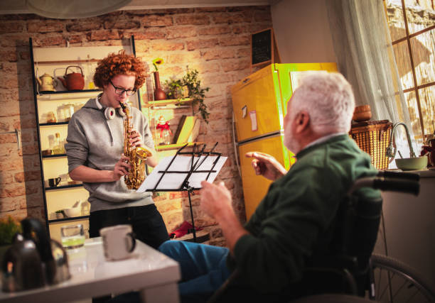 Happy senior man and grandson having fun while playing saxophone at home stock photo