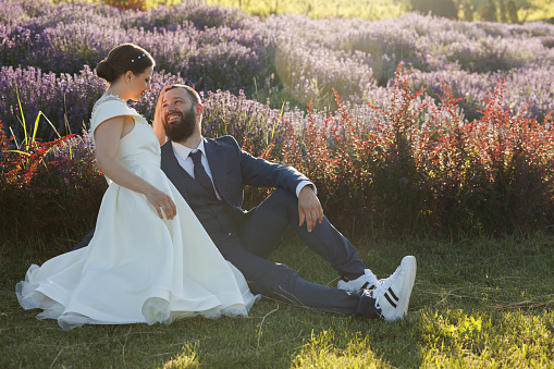 Happy just married couple sitting and hugging in lavender field
