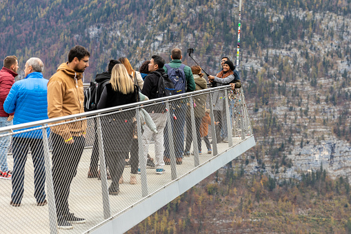 Hallstatt, Austria - November 2, 2019: Tourists scramble for taking photo on balcony of Memory of Mankind panoramic view point with background of mountain.