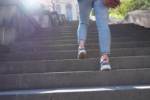Woman in sportswear climbs up stairs closeup. Walking and fitness concept