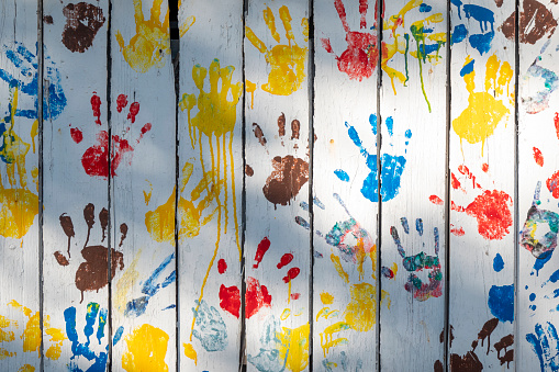 Wooden background with colored prints of children's palms