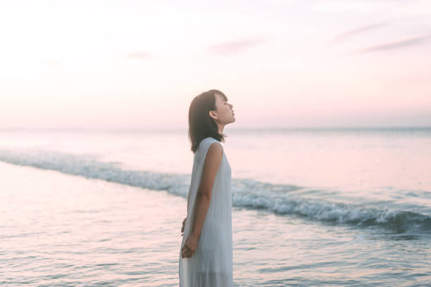 海の波の審美的な雰囲気の中でビーチレストでアジアの女性の肖像画 - 一人 ストックフォトと画像