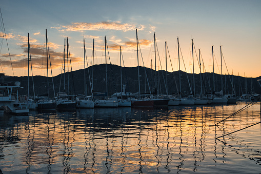 Saint-Florent, France - September 20, 2022. View of the marina of this tourist town of Corsica during the sunset that reflects in the Mediterranean Sea.