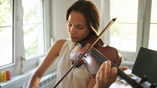 Young female violinist practicing at home stock photo