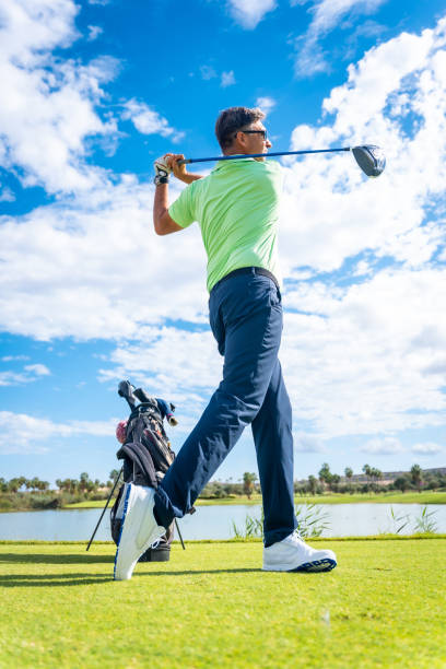 istock A player playing golf on the golf course, hitting the ball next to a lake, vertical photo 1428618072