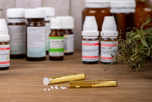 Homeopathy globules and vials on a table with bottles of globules