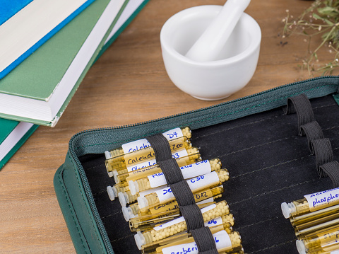 Homeopathy globules and vials on a table with old books