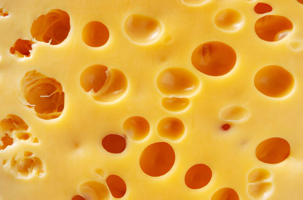 Texture of the yellow cheese with large holes.