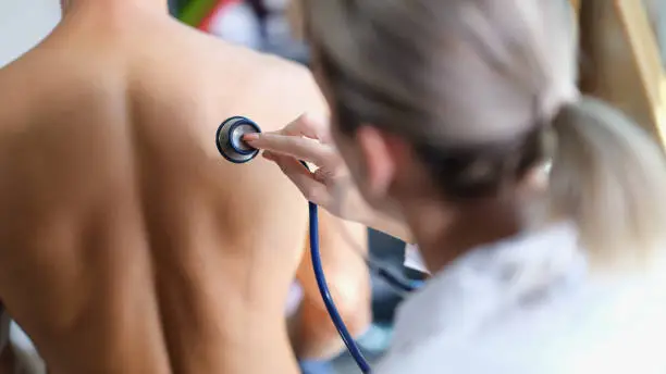 Photo of Young doctor examines the patient lungs with stethoscope