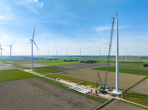 Wind turbine construction with huge cranes at a new wind park in Flevoland, Netherlands. Aerial view drone photo from above.