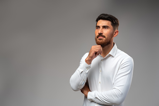 Studuo shot of thinking businessman standing over gray background close up