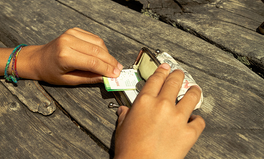 Niño tomando dinero de una billetera en una mesa de madera para pagar photo