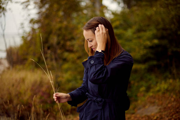 Autumn mood in nature with model. Waist up portrait mid adult woman picking some straw