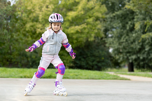 Young child learning how to ride roller skates outdoors