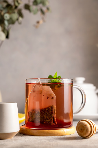 Cup of tea in glass mug with lemon, honey and mint leaves. Lifestyle warm drink. Relaxation concept