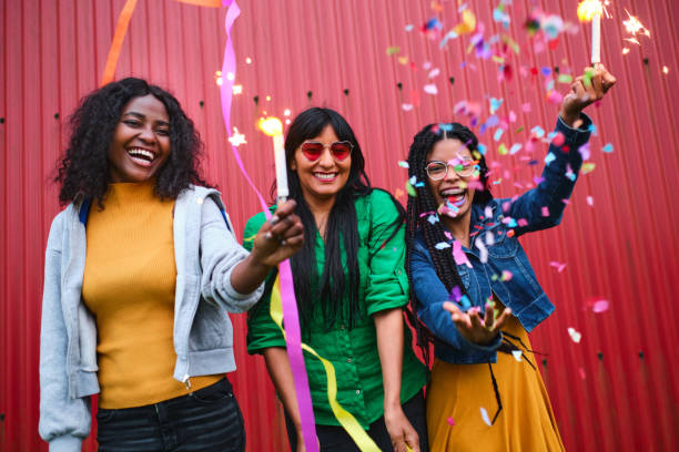 istock Three friends celebrating with candles and confetti outdoors on a red background 1428639878