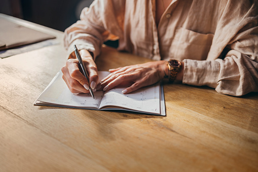 A cropped photo of an anonymous Caucasian entrepreneur holding a pen and taking some notes.