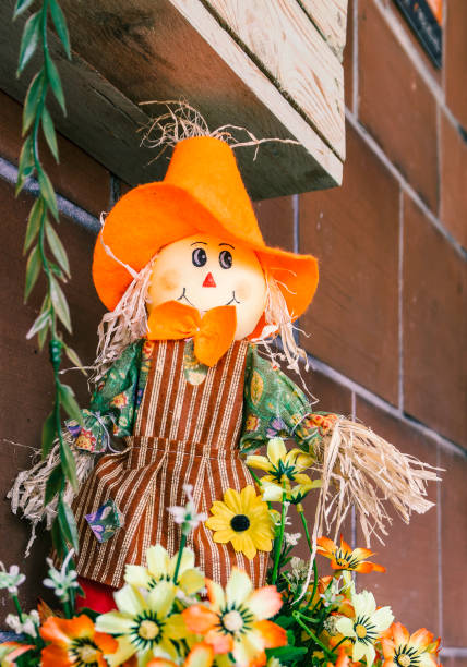 istock Smiling scarecrow doll with orange hat. Autumn decorations. Country style 1428640087