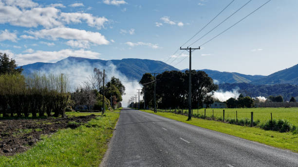 Smoke from an orchard prunings burn off bonfire obscuring a road Smoke from an orchard prunings burn off bonfire obscuring a road, filling the valleys and lungs with acrid smoke, Motueka, Tasman Region, south island, Aotearoa / New Zealand. motueka photos stock pictures, royalty-free photos & images