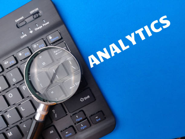 istock Wireless keyboard and magnifying glass with the word ANALYTICS on blue background. 1428641987