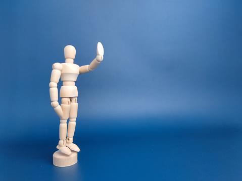 Wooden mannequin with action on a blue background with copy space.