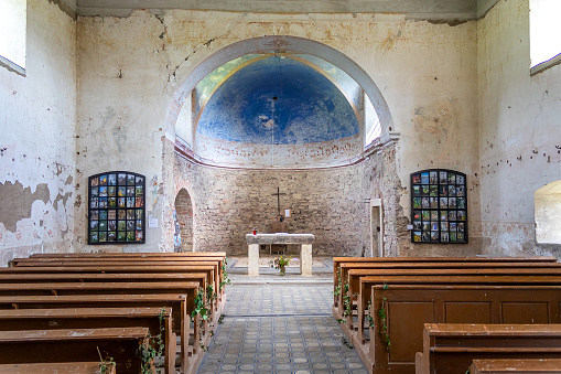 interior of the old abandoned church of St. John of Nepomuk with stone walls, view from behind the pews to the presbytery and altar, Bartosovice, Czech republic